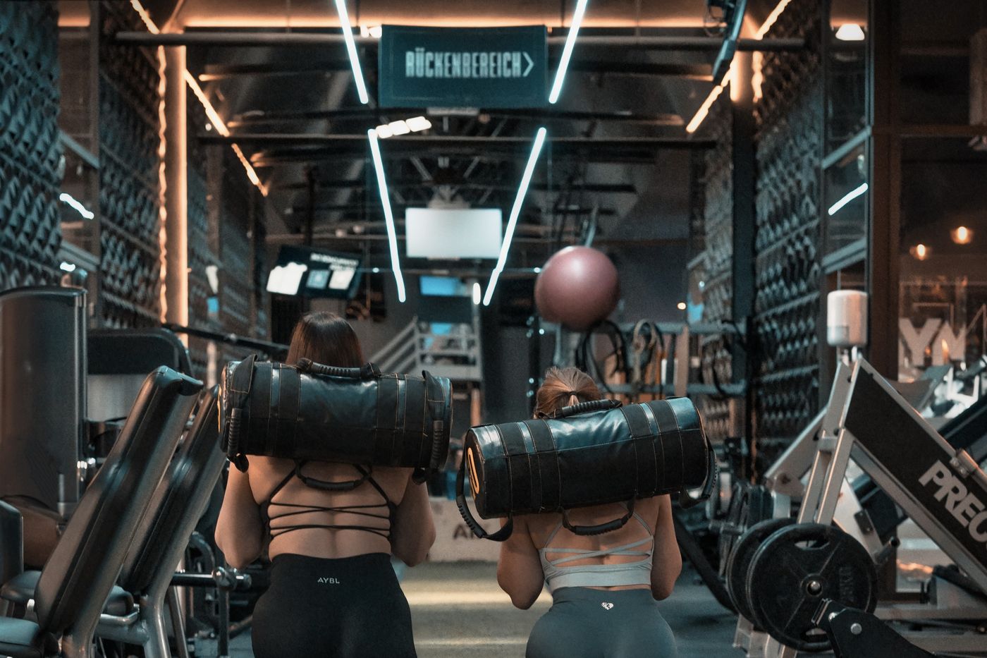 Freundinnen beim Sandbag-Training im Rückenbereich des GymOne 24/7 Bitburg