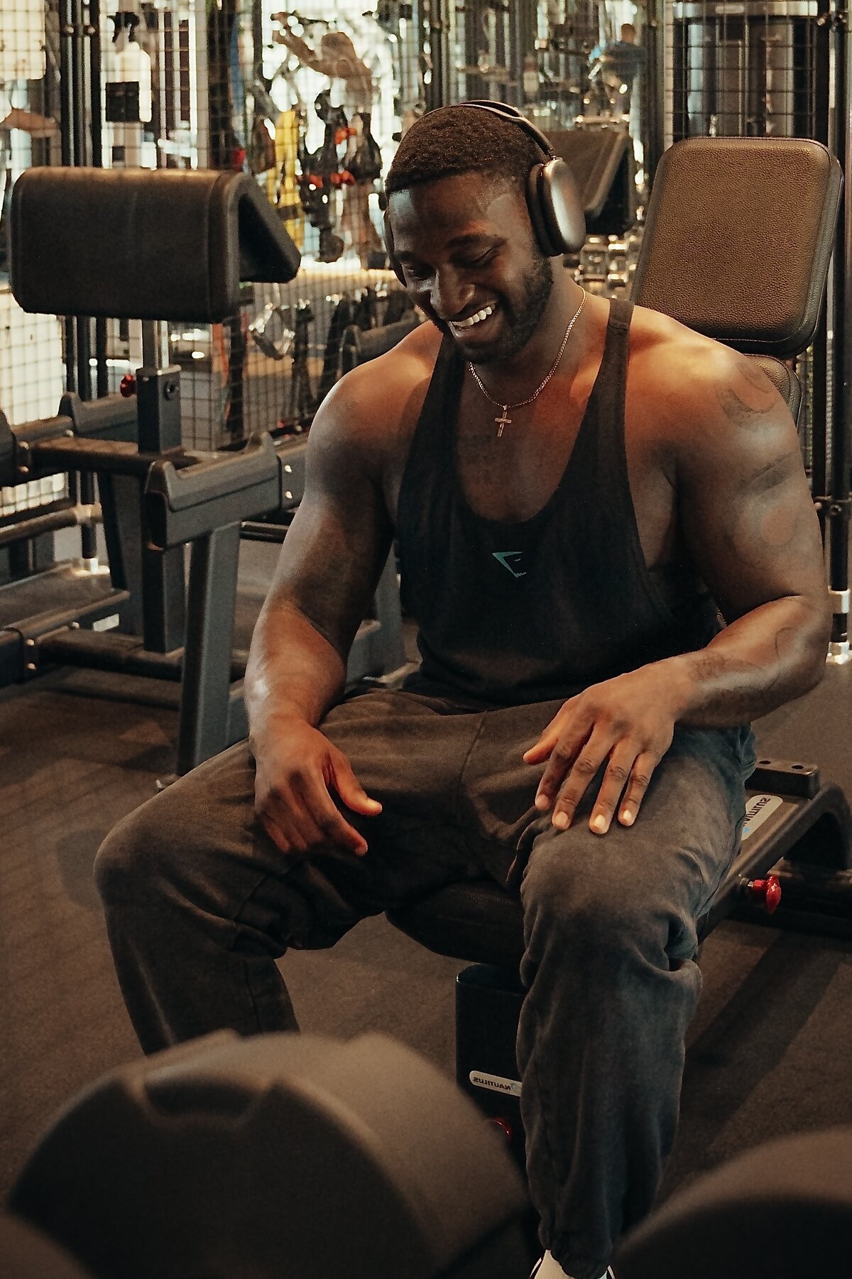 Mitglied mit Kopfhörern trainiert lächelnd im Kraftbereich des Fitnessstudio Bitburg GymOne 24/7